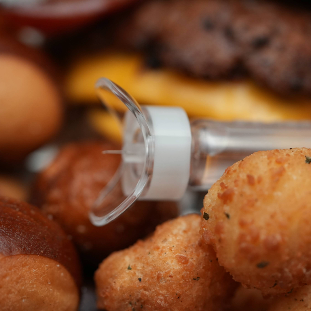 Steady Shot small size attached to 4mm insulin pen needle with cheese curds and a burger in the background. Diabetic-friendly tool for precise injection site rotation. Ideal for use during diabetes meal prep and balanced food enjoyment.
