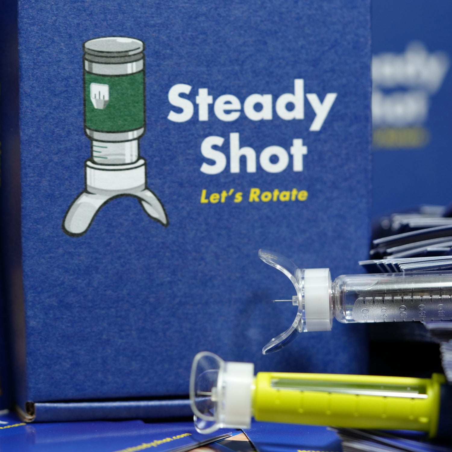 Steady Shot small and large sizes attached to insulin pen needle with 'Let’s Rotate' packaging in the background. Reusable diabetes tool for precise injection site rotation and improved comfort.